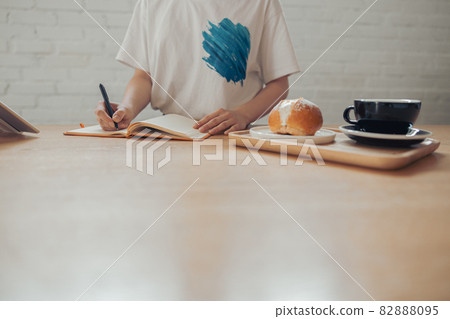 Young woman writing in notebook in coffee shop Young woman writing in notebook in coffee shop 82888095