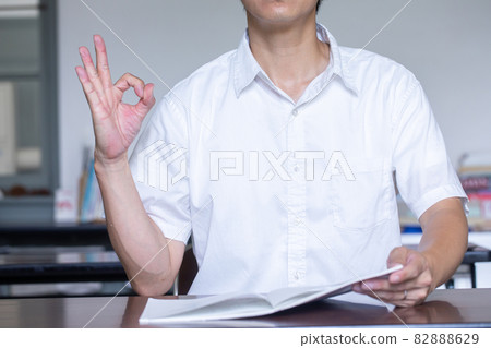 一個在辦公桌前打開一本書並發送簽名的人 一個發送簽名的人 82888629