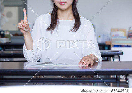 A woman who opens a book at a desk and sends a signature A person who sends a signature 82888636