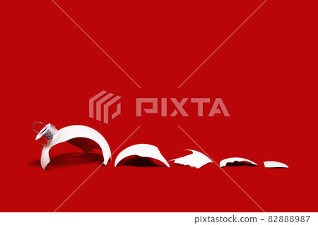 White broken glass bauble on red Christmas background. White broken glass bauble on red Christmas background. 82888987