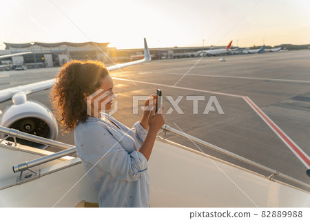 Pretty young woman holding mobile phone in airport Pretty young woman holding mobile phone in airport 82889988