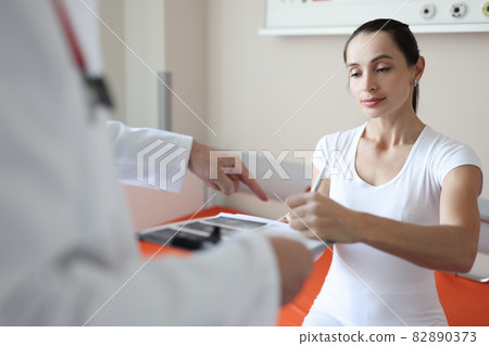 Woman patient signs medical documents at doctor appointment Woman patient signs medical documents at doctor appointment 82890373
