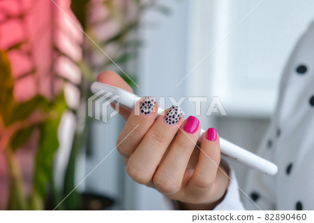Manicured female hands with stylish pink nails holding mobile phone. Smartphone technology. Trendy modern design manicure. Gel nails. Skin care. Beauty treatment. Nail care. Trendy colors Manicured female hands with stylish pink nails holding mobile phone. Smartphone technology. Trendy modern design manicure. Gel nails. Skin care. Beauty treatment. Nail care. Trendy colors 82890460