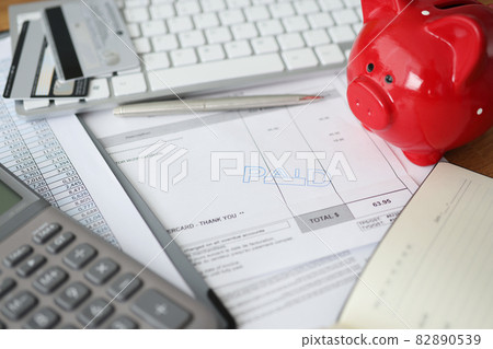 Invoice with paid stamp with bank cards and piggy bank on table Invoice with paid stamp with bank cards and piggy bank on table 82890539