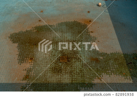 A dirty, abandoned swimming pool without water. 82891938