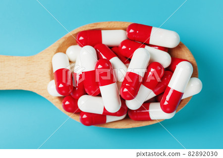 Red and white pill capsules on a blue background. Red and white pill capsules on a blue background. 82892030