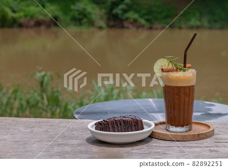 Honey lemon coffee with Chocolate Brownie Cake on wooden background with river view. 82892251