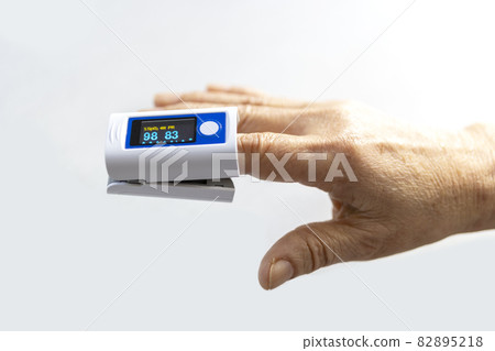Elderly finger and pulse oximeter seen from the side White background Elderly finger and pulse oximeter seen from the side White background 82895218