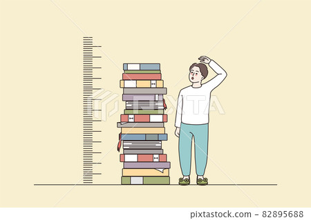Boy measuring growth stand near books pile 82895688