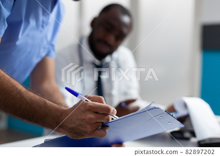 Closeup of physician man nurse checking ill symptoms on clipboard Closeup of physician man nurse checking ill symptoms on clipboard 82897202