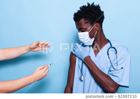 Doctor preparing to vaccinate nurse with face mask 82897210