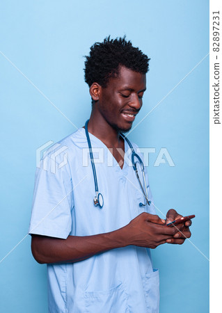 Man working as nurse looking at smartphone and smiling 82897231