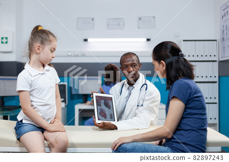 African american pediatrician doctor holding tablet computer with heart radiography 82897243