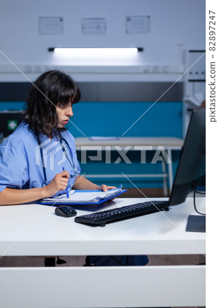 Medical assistant analyzing documents and files on monitor Medical assistant analyzing documents and files on monitor 82897247