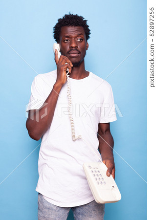 Young adult answering retro telephone with wire Young adult answering retro telephone with wire 82897256