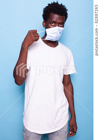 Portrait of person putting mask on face in studio 82897265