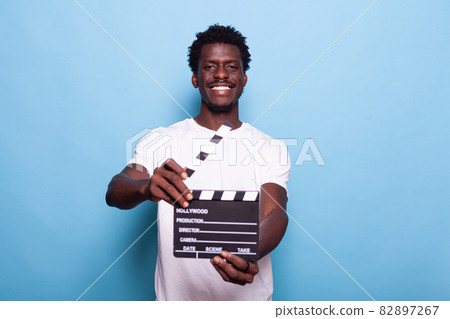 Portrait of man holding clapperboard to cut scenes Portrait of man holding clapperboard to cut scenes 82897267
