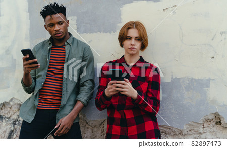 Young biracial couple addicted to smartphones outdoors in town, social media concept 82897473