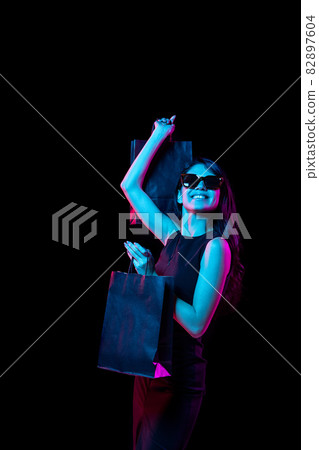 Portrait of young woman in neon light on dark backgound. Human emotions, black friday, cyber monday, purchases, sales, finance concept. 82897604