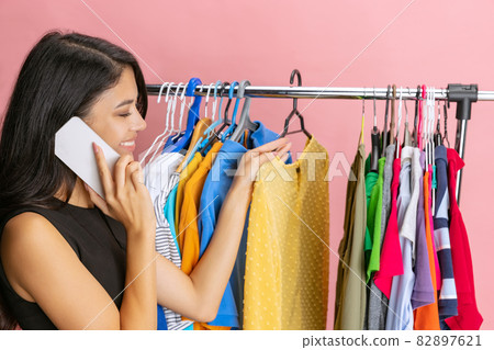 Beautiful young girl chooses clothes, outfit, dress in clothing store. Wow emotions, black friday, cyber monday, purchases, discount, ad. 82897621