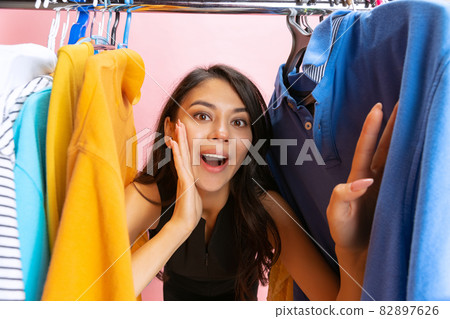 Beautiful young girl chooses clothes, outfit, dress in clothing store. Wow emotions, black friday, cyber monday, purchases, discount, ad. 82897626