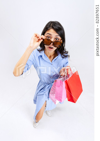 Stylish young girl shopping while black friday sales. Model with lots of bags, colorful bright packages isolated over white studio background. 82897651