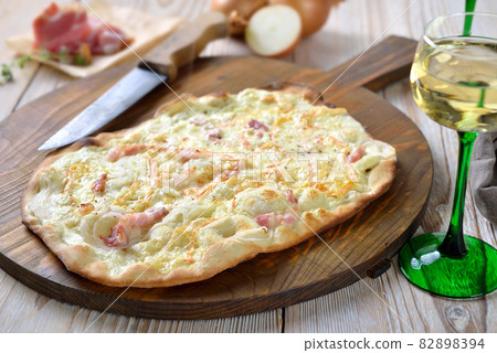 Tarte flambee from Alsace with onions, smoked bacon and munster cheese Tarte flambee from Alsace with onions, smoked bacon and munster cheese 82898394