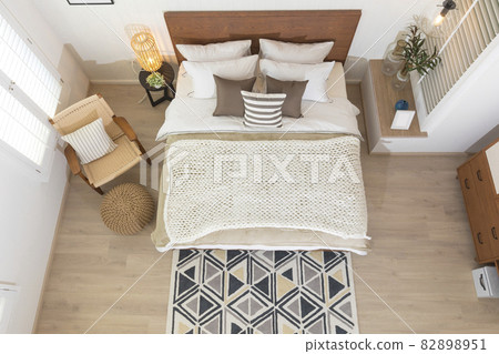 Interior of modern bedroom with white mattress, wooden floor, armchair and brown pillow setting. Top view of spacious bedroom. Interior of modern bedroom with white mattress, wooden floor, armchair and brown pillow setting. Top view of spacious bedroom. 82898951