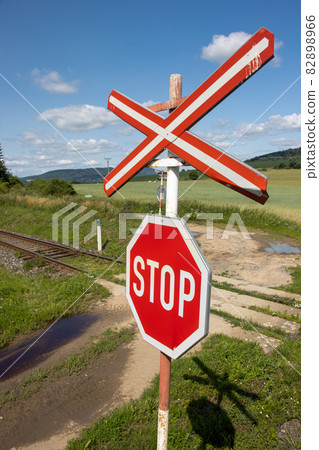 A red STOP sign before crossing the tracks. 82898966