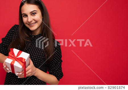 Closeup photo shot of beautiful happy smiling brunette female teenager isolated over red background 82901874