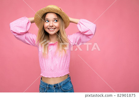 Portrait of young attractive smiling hipster blonde woman in stylish pink crop top and straw hat 82901875