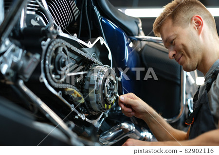 Master repairing motorcycle in workshop using wrench Master repairing motorcycle in workshop using wrench 82902116