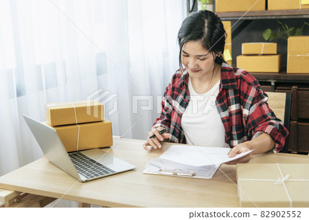 Online seller Close up hands Young asian woman typing laptop keyboard checking online order, check goods stock delivery package shipping postal. Asian woman startup small business at home office 82902552