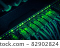 Close up of green network cables from data center connected with patch cord to black switch glowing in the dark 82902824