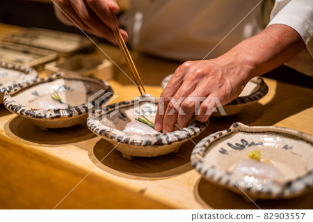 Itamae-san's hand preparing the sashimi Itamae-san's hand preparing the sashimi 82903557