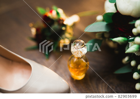 Pair of elegant and stylish bridal shoes with wedding rings and a bouquet of roses and other flowers Pair of elegant and stylish bridal shoes with wedding rings and a bouquet of roses and other flowers 82903699