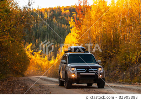 Mitsubishi Pajero on scenic autumn road in the forest 82905888