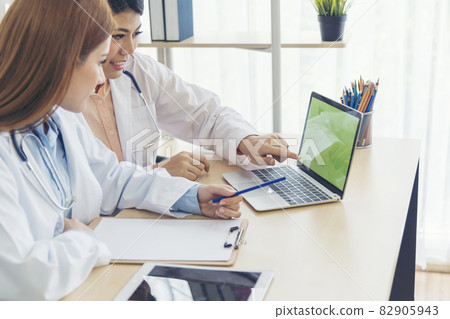 Two asian women doctors discuss meeting doctor's office medical clinic using laptop consulting patient disease. Asian medical lab young women talking together discussing healthcare assistance teamwork Two asian women doctors discuss meeting doctor's office medical clinic using laptop consulting patient disease. Asian medical lab young women talking together discussing healthcare assistance teamwork 82905943