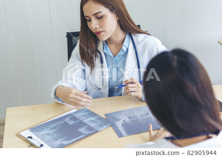 Young asian woman doctor meeting at office table. Two women doctors discussing diagnosis meeting in hospital office medical clinic looking x-ray film consulting patient disease medical lab discussion 82905944