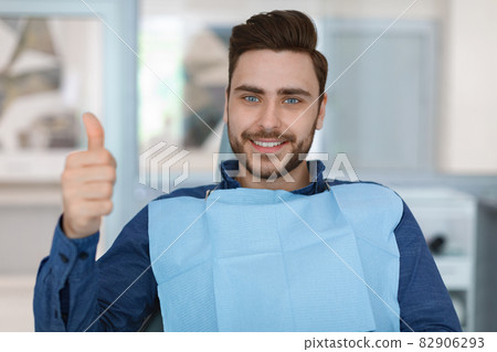 Young man patient smiling in dentistry, showing thumb up Young man patient smiling in dentistry, showing thumb up 82906293