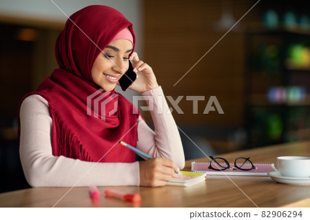 Beautiful muslim woman talking on cellphone at cafe 82906294