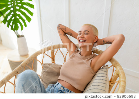 Weekend recreation. Young lady sitting in cozy modern chair with eyes closed, resting and relaxing at home 82906698