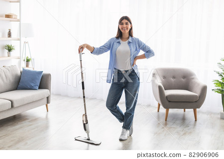 Portrait of cheerful lady cleaning floor with spray mop, posing 82906906