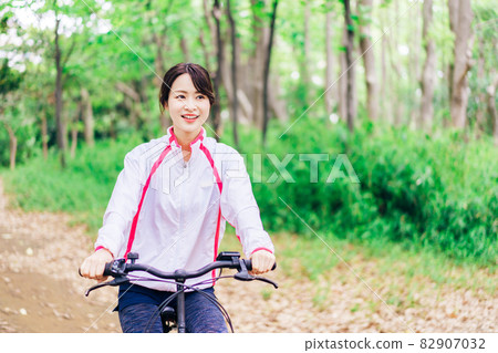 Young woman enjoying cycling in nature 82907032