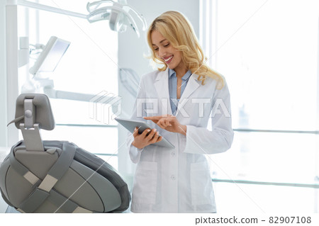 Blonde woman dentist using digital tablet at dental clinic Blonde woman dentist using digital tablet at dental clinic 82907108