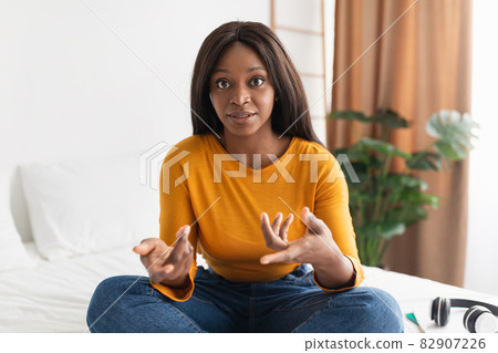 African American Lady Talking Looking At Camera Sitting In Bedroom 82907226