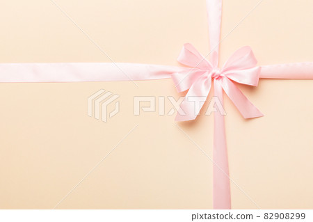 Top view of purple ribbon rolled and pink bow isolated on colored background. Flat lay with copy space 82908299