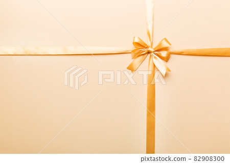 Top view of gold ribbon rolled and yellowbow isolated on colored background. Flat lay with copy space 82908300