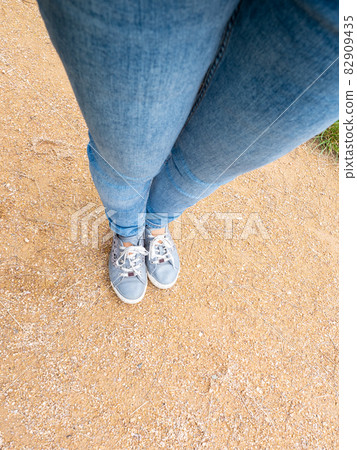 Looking down at my feet in tight jeans wearing hippie sneaker 82909435