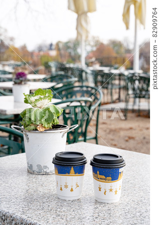 Houseplant in bucket and two recyclable paper coffee cups with christmas print  82909764